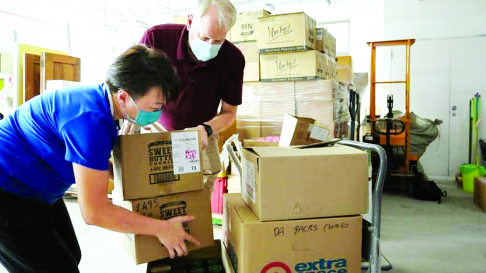 Bà Karen Yip và chồng - ông David Taylor - giải cứu những hộp thực phẩm chế biến sẵn mà họ dự định phân phát qua ứng dụng GoodHood.SG - ẢNH: CAN/MARCUS MARK RAMOS