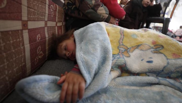 một đứa trẻ ngủ dưới tấm chăn trong một nơi trú ẩn tạm thời ở Nhà thờ Hồi giáo Al-Mansory ở thành phố cổ của quận Jableh.