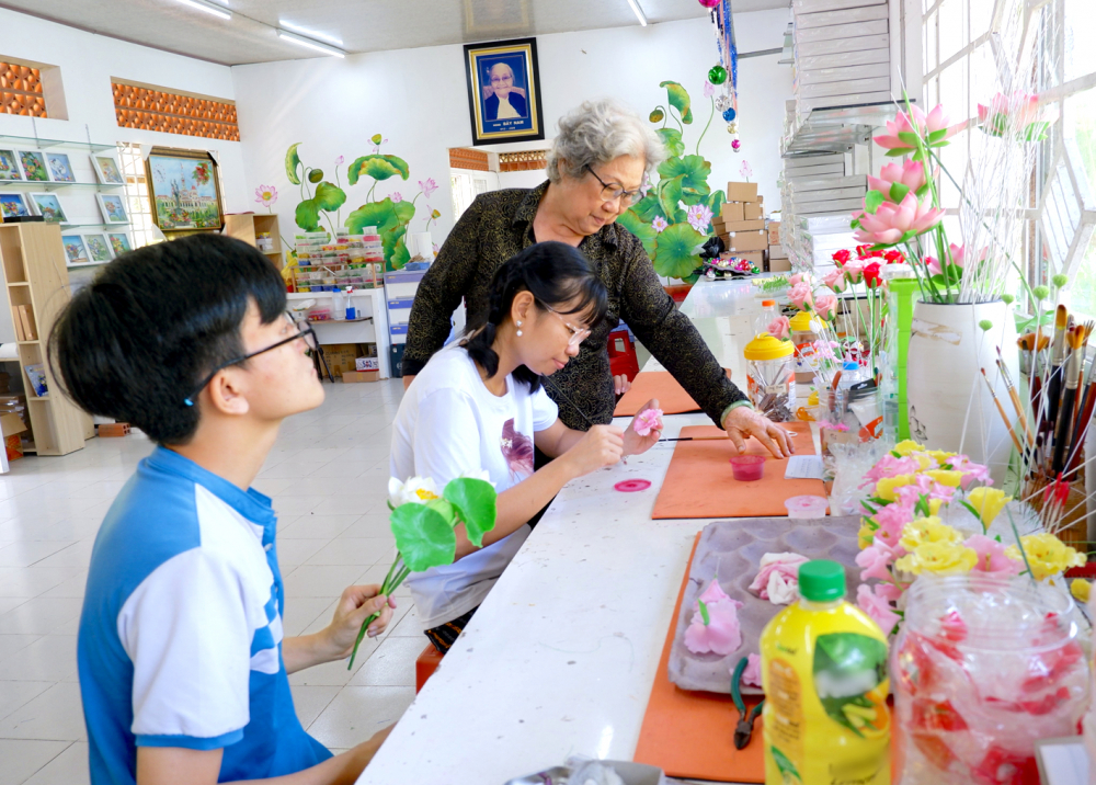 Cô Nguyễn  Thị Bảy đang hướng dẫn  các học viên khuyết tật  làm hoa đất  Ảnh: P.T.