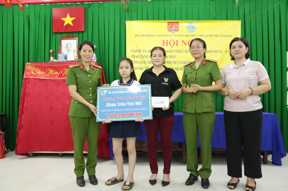 Đại úy Phùng Thị Thanh Phương (bìa trái) - Chủ tịch Hội Phụ nữ Phòng PC07 - trao tiền hỗ trợ bé Yến Nhi. 