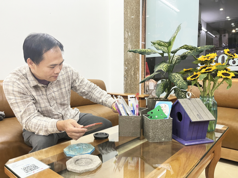 Ông Nguyễn Khắc Tiến - Giám đốc Công ty TNHH Phát triển xã hội Dấu Chân Xanh - bên các sản phẩm được tái chế từ vỏ hộp sữa - ẢNH: NGUYỄN CẨM