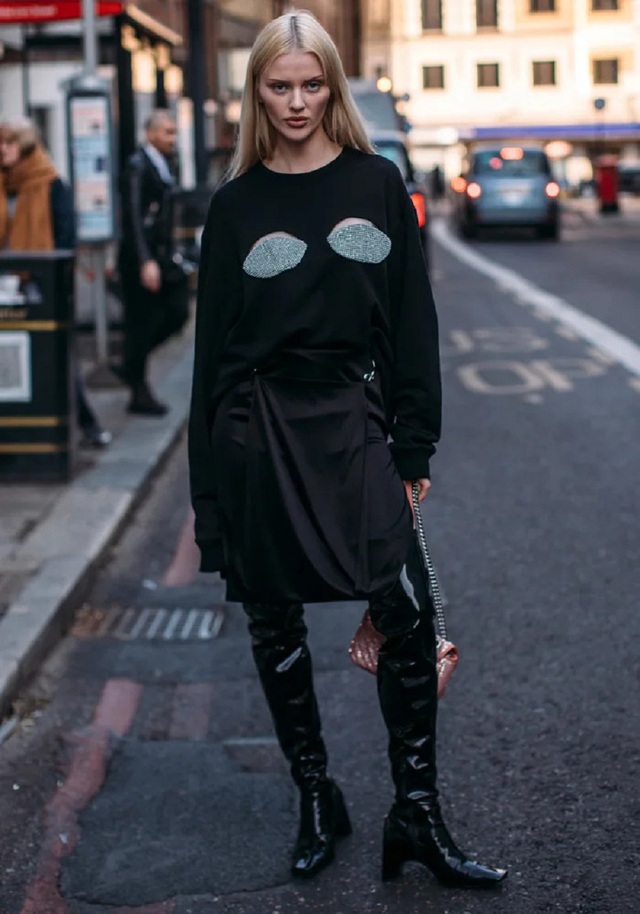 Người mẫu Elodie Russell chinh phục giới mộ điệu trong bộ trang phục được kết hợp từ áo len cut out táo bạo ở phần ngực, chân váy satin màu đen dài đến đầu gối và đi boots cao gót mũi vuông cổ điển.