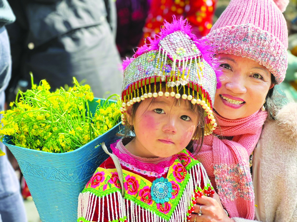 Em bé Hà Giang chụp ảnh cùng du khách trên dốc Thẩm Mã - Ảnh: Bùi Tiểu Quyên