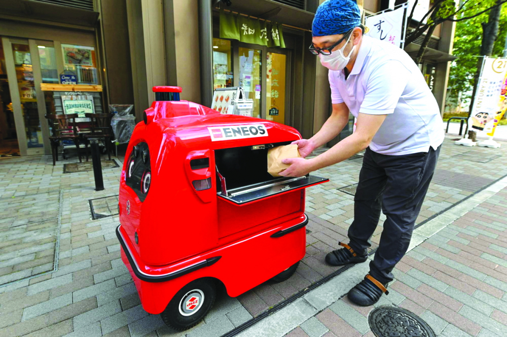 Robot giao hàng DeliRo của ZMP đang nhận một túi thức ăn để giao - ẢNH: AFP