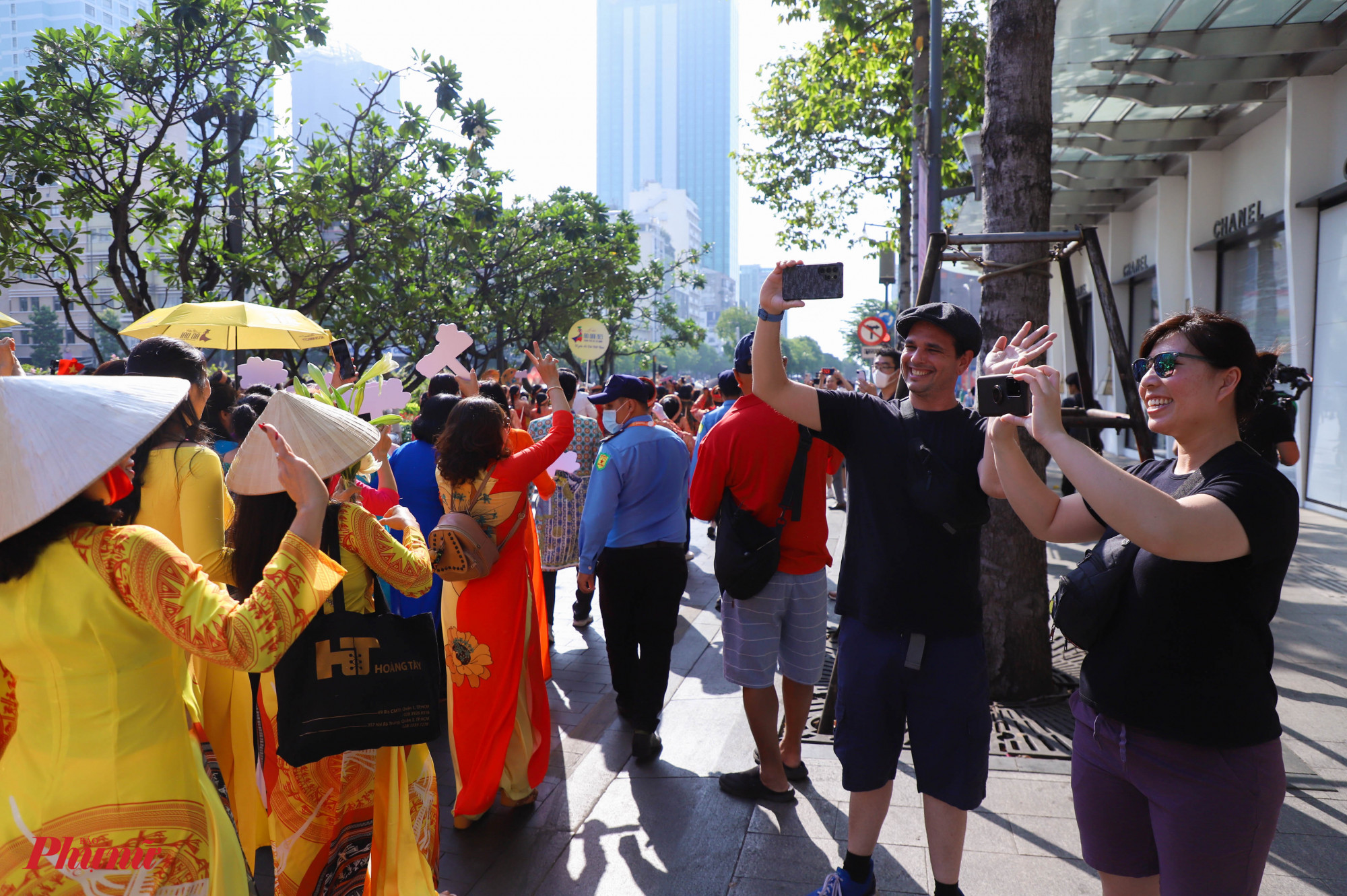 Du khách nước ngoài thích thú với hình ảnh của buổi diễu hành, dùng điện thoại 