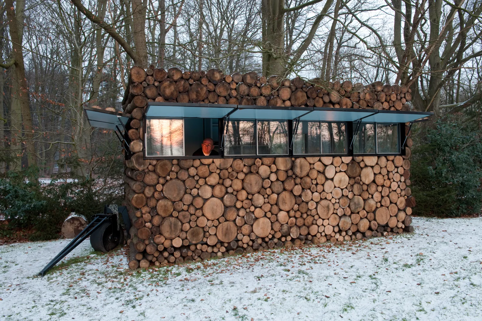 Mobile Log Cabin (Hà Lan) Nếu bạn chỉ đi ngang qua, sẽ rất dễ nhầm căn nhà gỗ này với một đống gỗ thực sự—đặc biệt là khi các cửa sổ được đóng lại. Được thiết kế bởi  Piet Hein Eek , không gian thực sự là một phòng thu âm nhạc được tạo ra cho Hans Liberg, một nhạc sĩ người Hà Lan. Bên trong, cabin được sơn màu xanh nhạt và được trang bị bàn làm việc, thiết bị ghi âm và giá sách tích hợp.