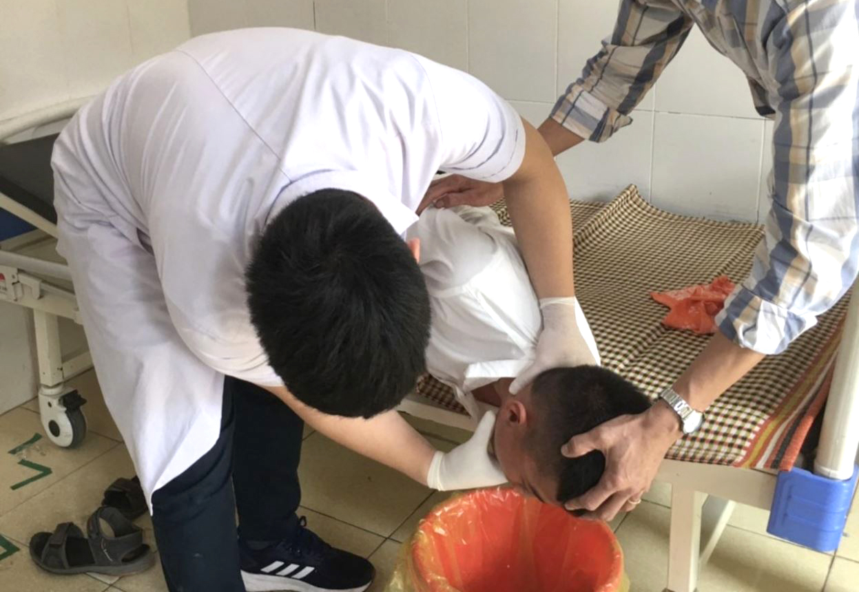 Các em học sinh được uống nước rửa dạ dày sau khi ăn phải hạt quả ngô đồng - Ảnh: Khánh Trung