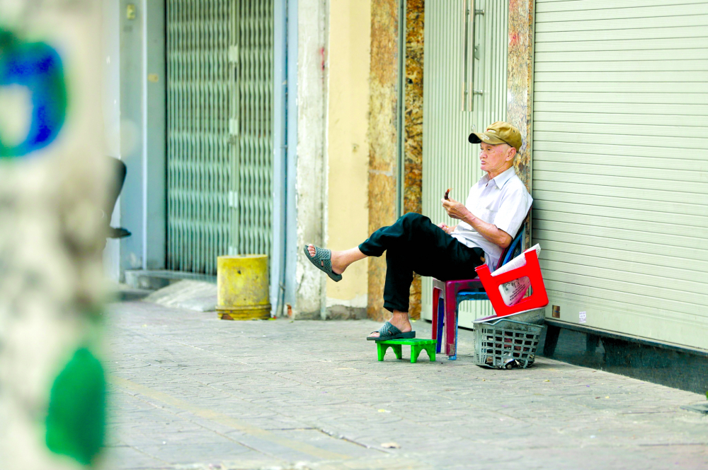 Nhiều người già sẽ cảm thấy cô đơn, lạc lõng trong bối cảnh công nghệ phát triển (trong ảnh: Một người đàn ông ngồi lặng lẽ ngắm phố phường trên vỉa hè đường Nguyễn Đình Chiểu, quận 3) ẢNH: TAM NGUYÊN