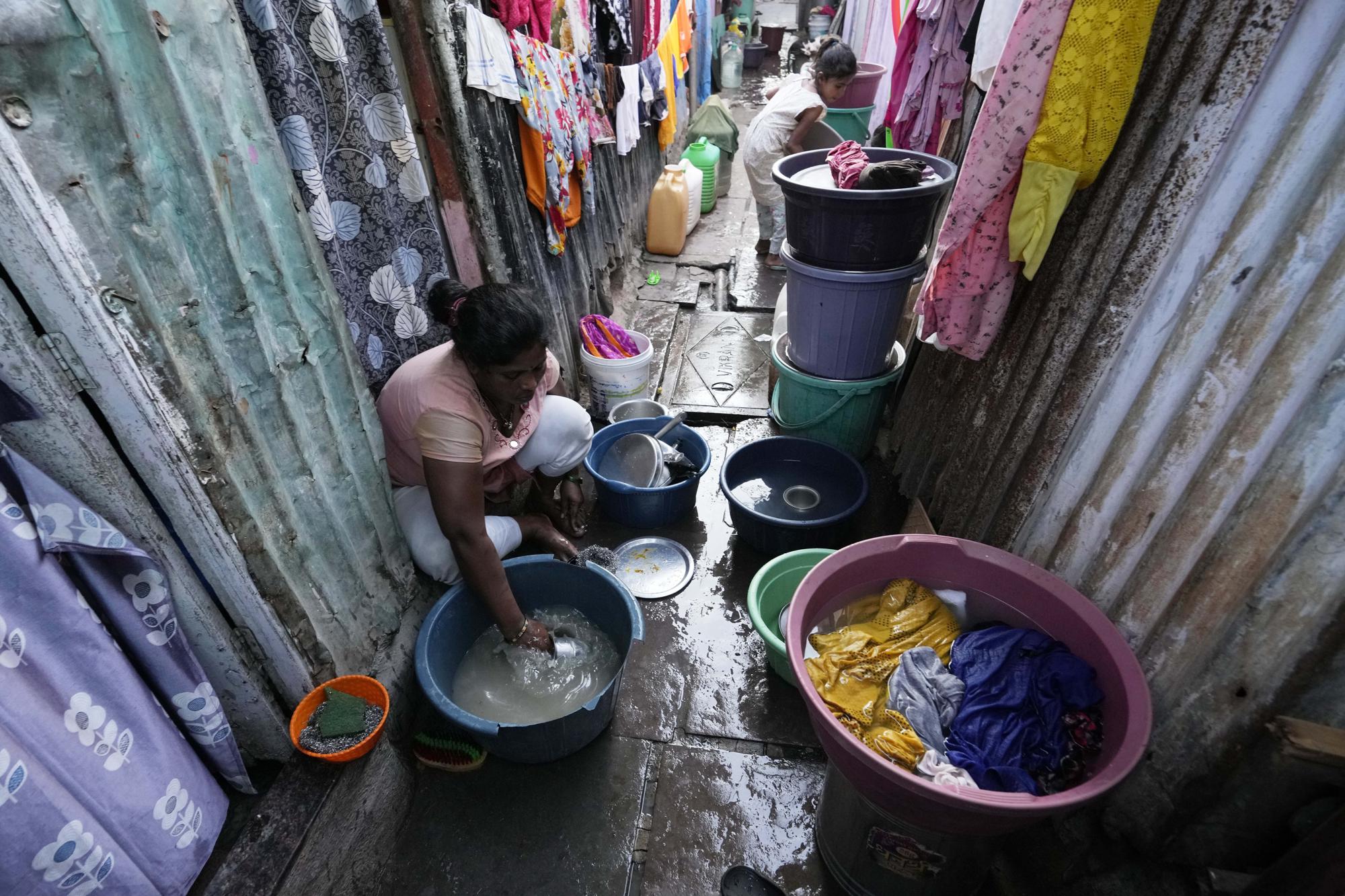 Một phụ nữ Ấn Độ đang nấu nướng, giặt giũ tại khu nhà ổ chuột