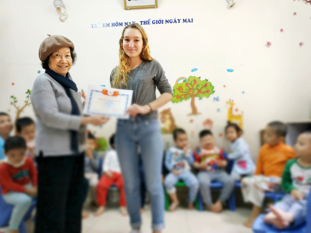 Một tình nguyện viên người nước ngoài (bìa phải) chụp hình kỷ niệm với bà Nga  và học sinh Trung tâm Hy Vọng