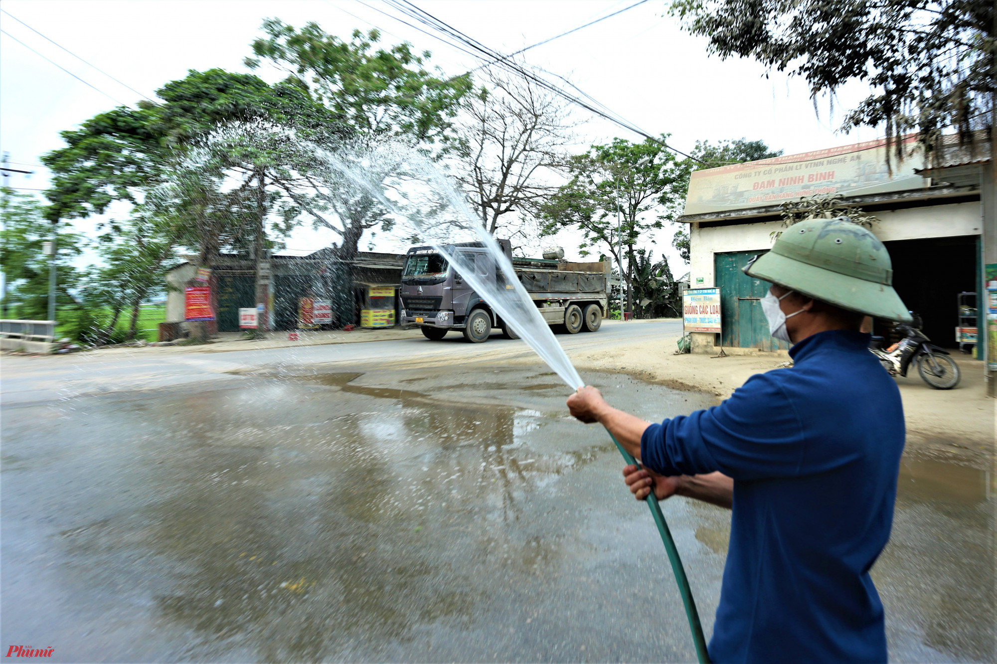 Ngày vài lần, ông Bình lại phải bật chiếc máy bơm công suất lớn để tưới đoạn đường trước nhà, đẩy lớp đất cát rơi vãi trên đường đi để giảm bớt bụi. 