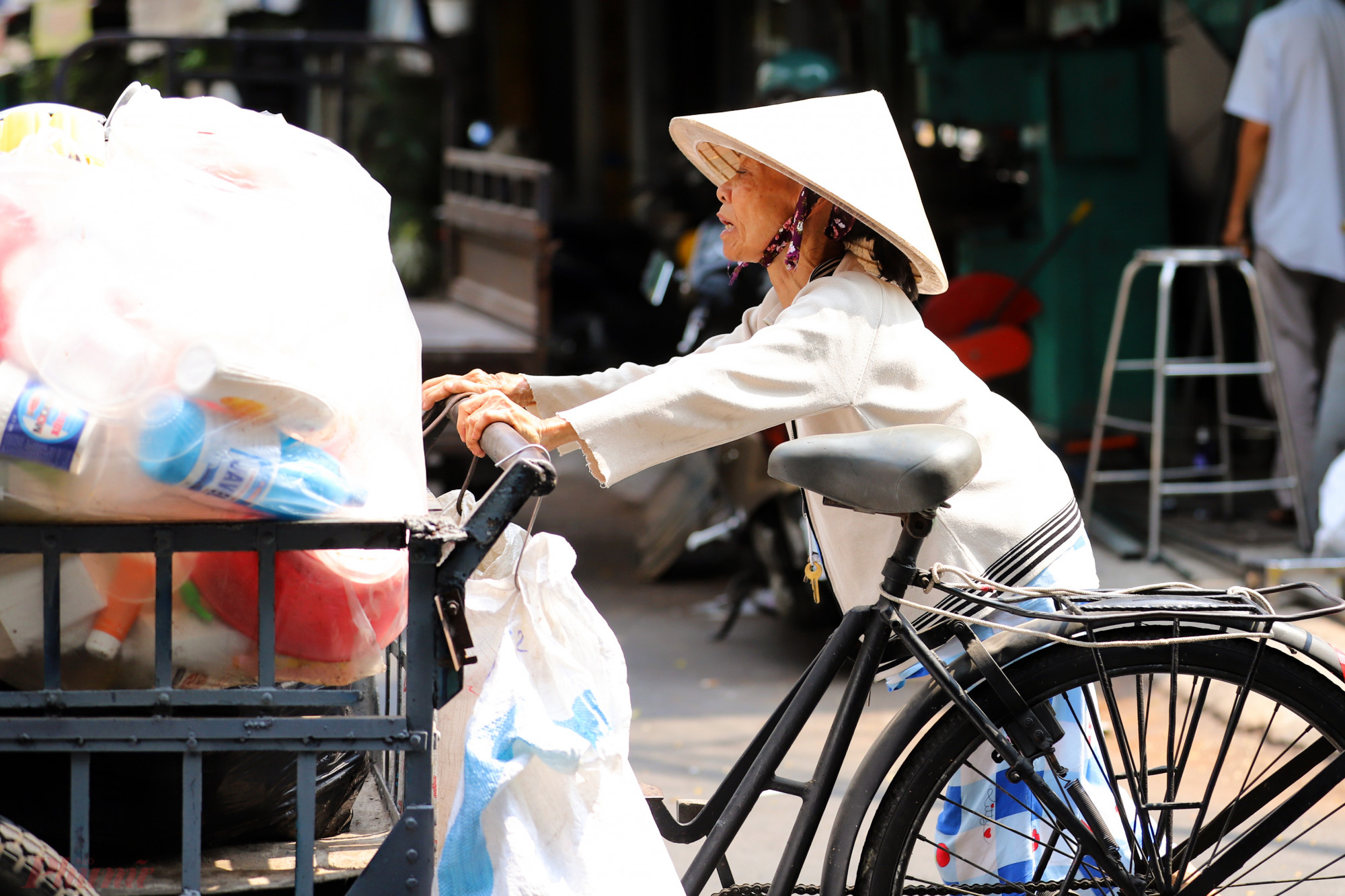 Người phụ nữ tỏ ra mệt mỏi khi phải đẩy chiếc xe ve chai di chuyển giữa thời tiết lên đến 35 độ C.