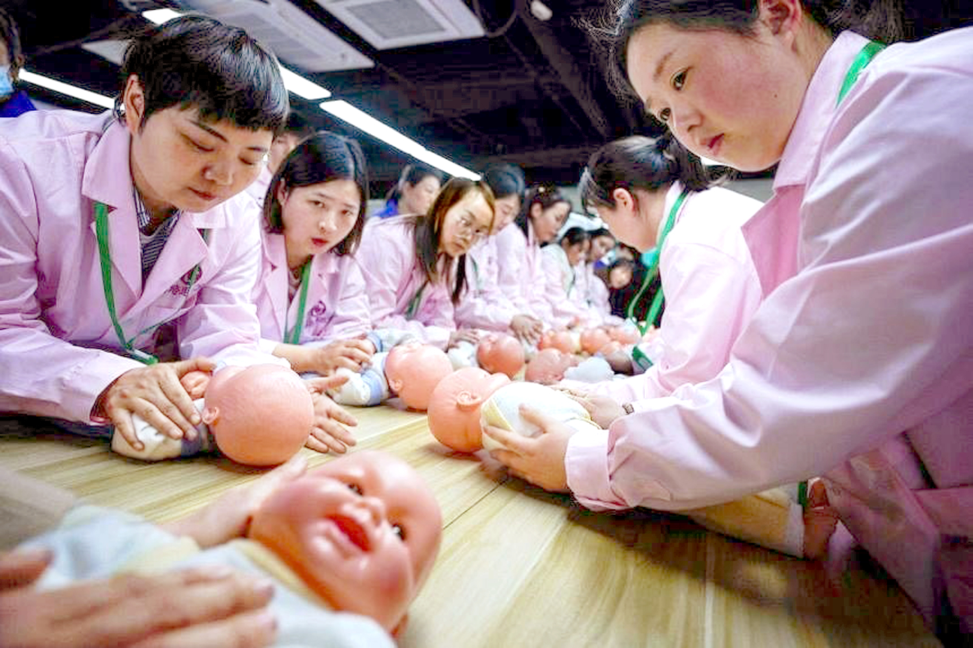 Học viên đang thực hành chăm sóc trẻ sơ sinh tại các lớp kỹ năng bảo mẫu ở Thượng Hải (Trung Quốc) - ẢNH: REUTERS