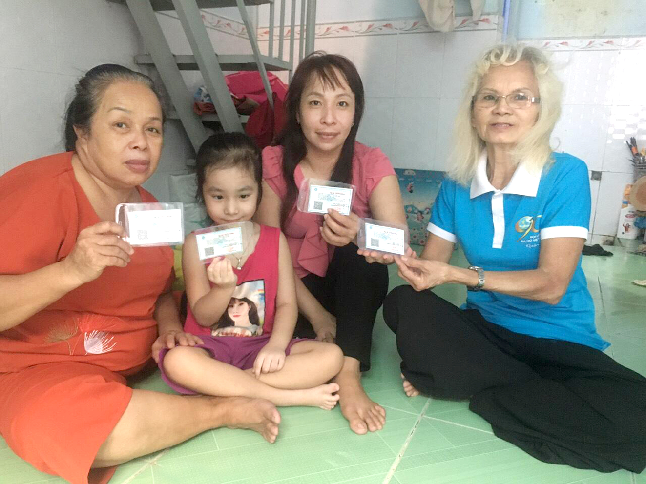 Bà Thơm Em (bìa phải) tặng thẻ bảo hiểm y tế cho 1 gia đình khó khăn