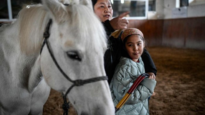 Mộ bé gái mắc chứng tự kỷ ở Trung Quốc đang tham gia các hoạt động với ngựa - Ảnh: 