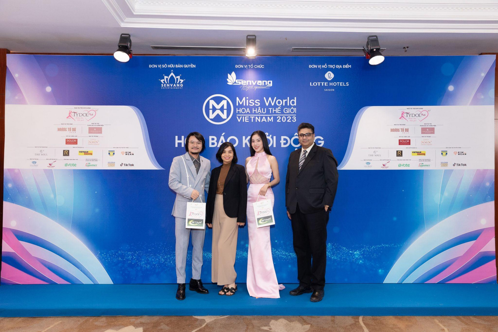 Thạc sĩ Phạm Kim Dung và đạo diễn Hoàng Nhật Nam nhận quà tặng từ TYDOL Plus tại thảm đỏ Họp báo Khởi động Miss World Vietnam 2023 - Ảnh: RV-OPV