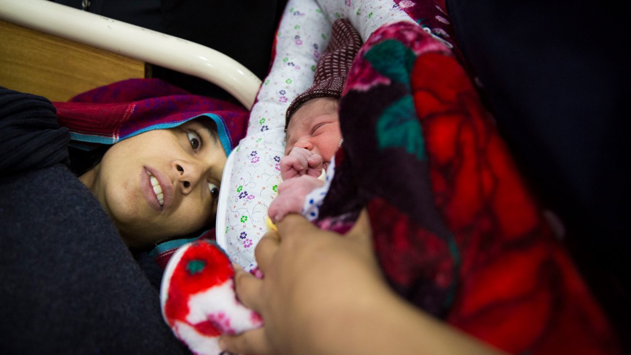 Sau khi được cấp cứu khỏi tai biến băng huyết, một người mẹ trẻ người Pakistan ngắm đứa con vừa chào đời của cô. (Ảnh: Saiyna Bashir/Wellcome Trust)