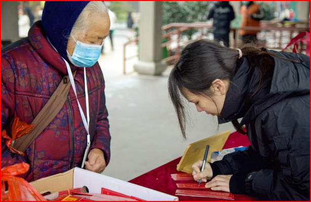 Tình nguyện viên Lu Zi viết lời chúc cho một vị khách lớn tuổi trong Lễ hội đèn lồng tại một ngôi chùa ở Gia Hưng, tỉnh Chiết Giang. Ảnh: Tài liệu phát tay