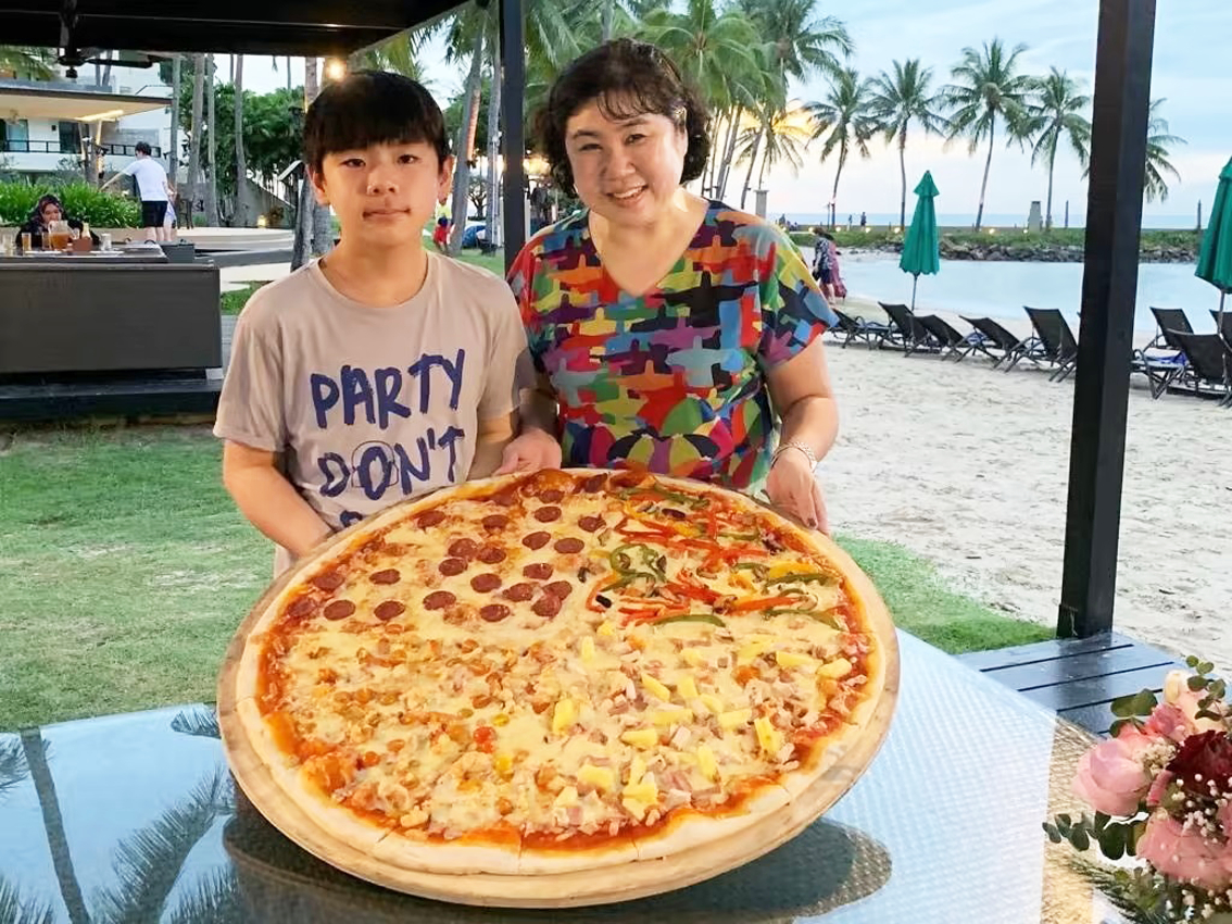 Cô Stella Thng cùng con trai Ayden tận hưởng cảnh hoàng hôn trên bãi biển với một chiếc bánh pizza khổng lồ - ẢNH: STELLA THNG