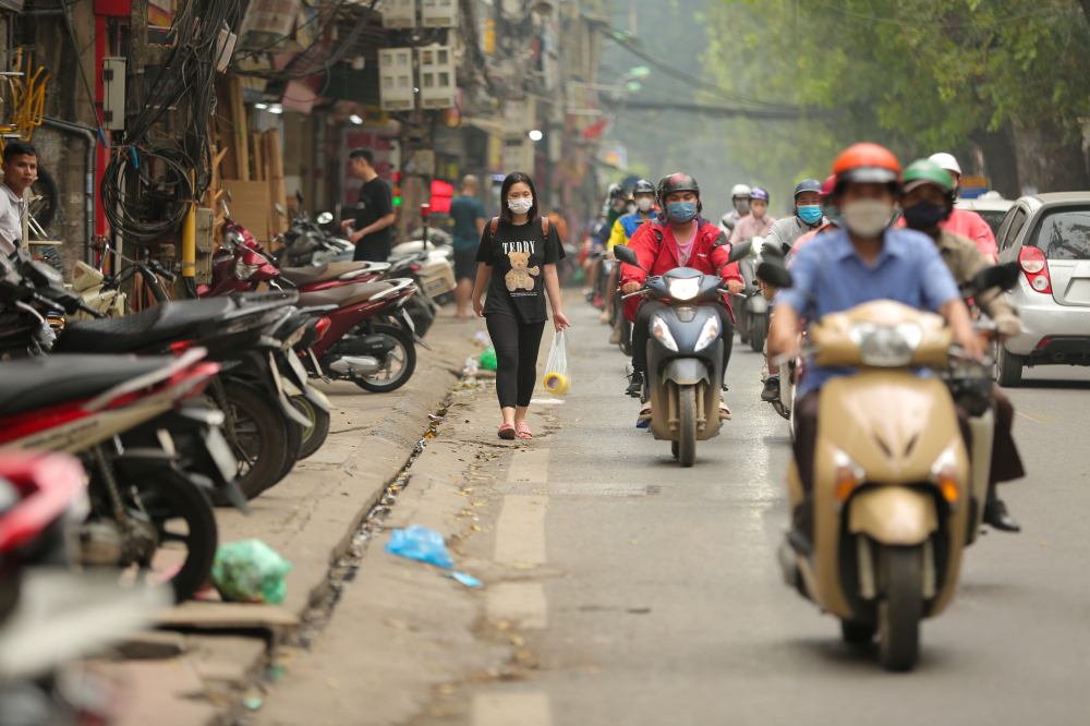 Ở một đoạn đường khác, vỉa hè được dùng để đỗ xe máy của các cửa hàng, người đi bộ lại tiếp tục bị đẩy xuống lòng đường.
