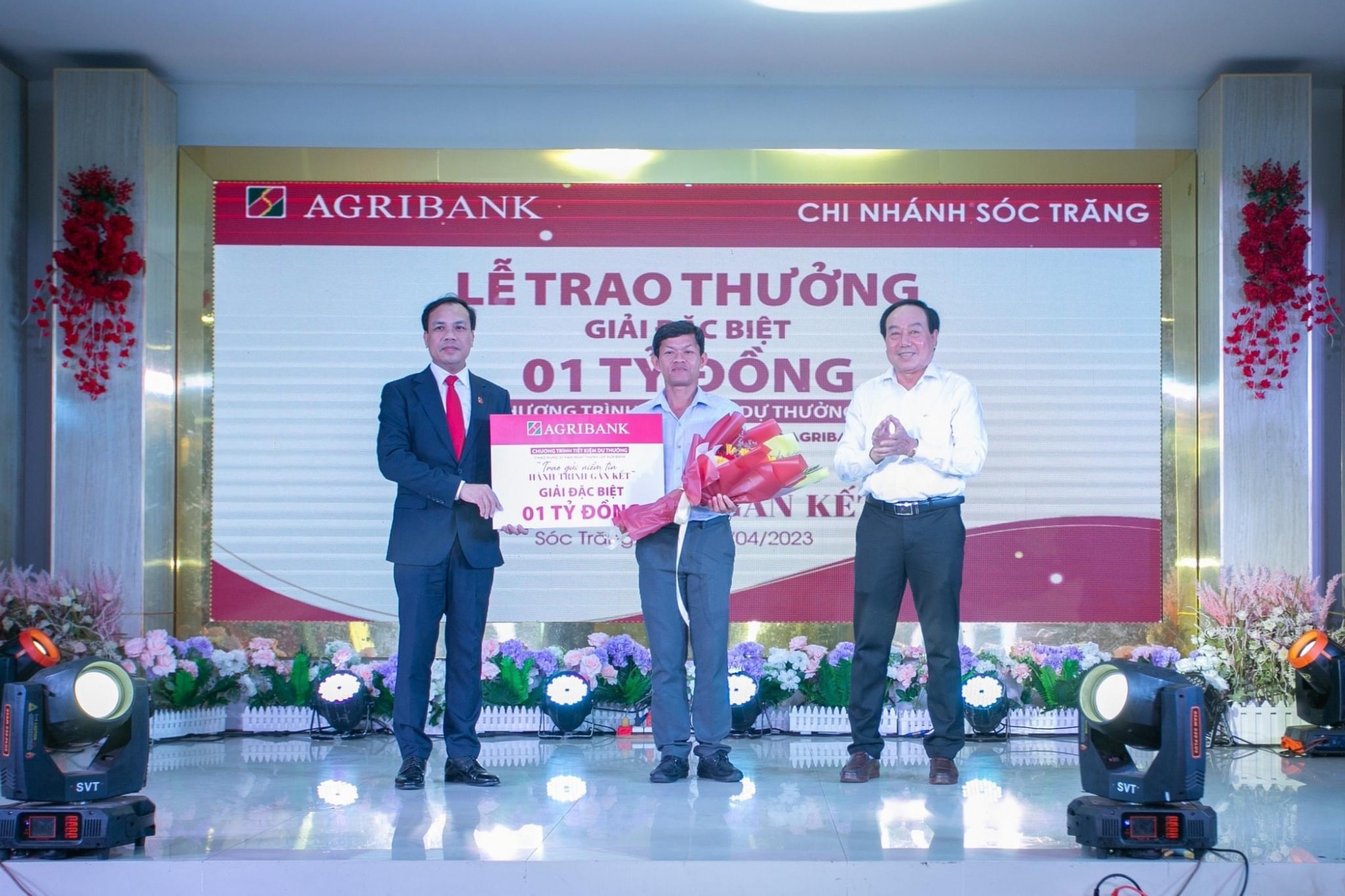 Đại diện lãnh đạo Agribank - Phó tổng giám đốc Lê Hồng Phúc trao 1 tỉ đồng cho khách hàng trúng giải Đặc biệt - Ảnh: Agribank