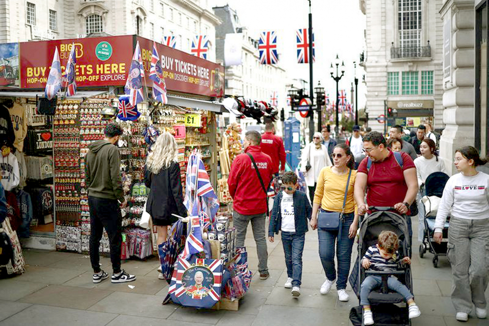 Người dân và du khách đi ngang qua một ki ốt lưu niệm bán các mặt hàng theo chủ đề Lễ đăng quang tại London, Anh - ẢNH: REUTERS