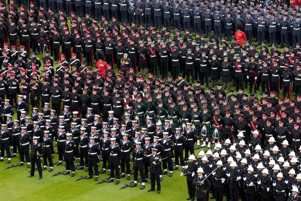 Các thành viên của lực lượng vũ trang đứng thành đội hình trên bãi cỏ bên ngoài Cung điện Buckingham