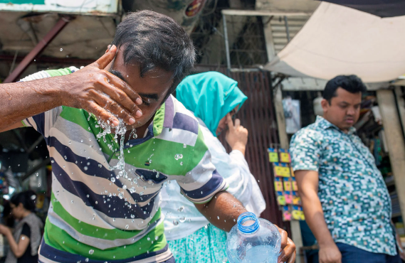 Một người đàn ông té nước lên mặt vào tháng trước để giải nhiệt ở Dhaka. Đã có báo cáo về những con đường tan chảy ở thủ đô của Bangladesh vì nắng nóng gay gắt. Ảnh: EPA-EFE