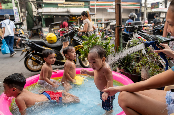 Trẻ em chơi trong một bể bơi bơm hơi bên cạnh một con phố ở Manila vào tháng trước giữa thời tiết nóng bức. Ảnh: Reuters