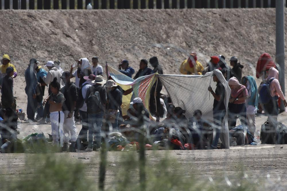 Người di cư chờ chính quyền Mỹ, giữa hàng rào dây thép gai và hàng rào biên giới tại biên giới Mỹ-Mexico, nhìn từ Ciudad Juarez, Mexico. (Ảnh: AP)