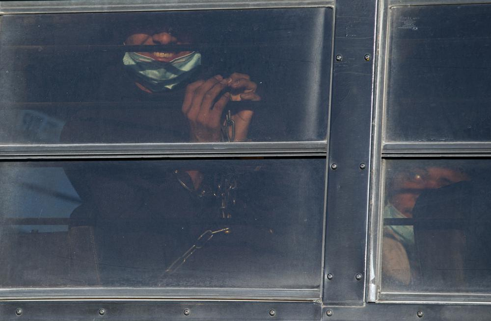 Một người di cư bị xích mỉm cười khi được vận chuyển bằng xe buýt để lên chuyến bay hồi hương của Cơ quan Thực thi Di trú và Hải quan Mỹ đến Guatemala từ El Paso, Texas hôm 10/5. (Ảnh: AP)