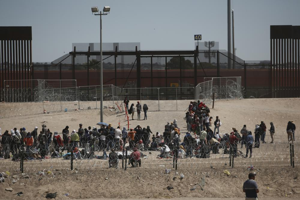 Người di cư chờ lực lượng chức năng Mỹ, giữa hàng rào dây thép gai và hàng rào biên giới ở biên giới Mỹ-Mexico, nhìn từ Ciudad Juarez, Mexico ngày 10/5. (Ảnh: AP)