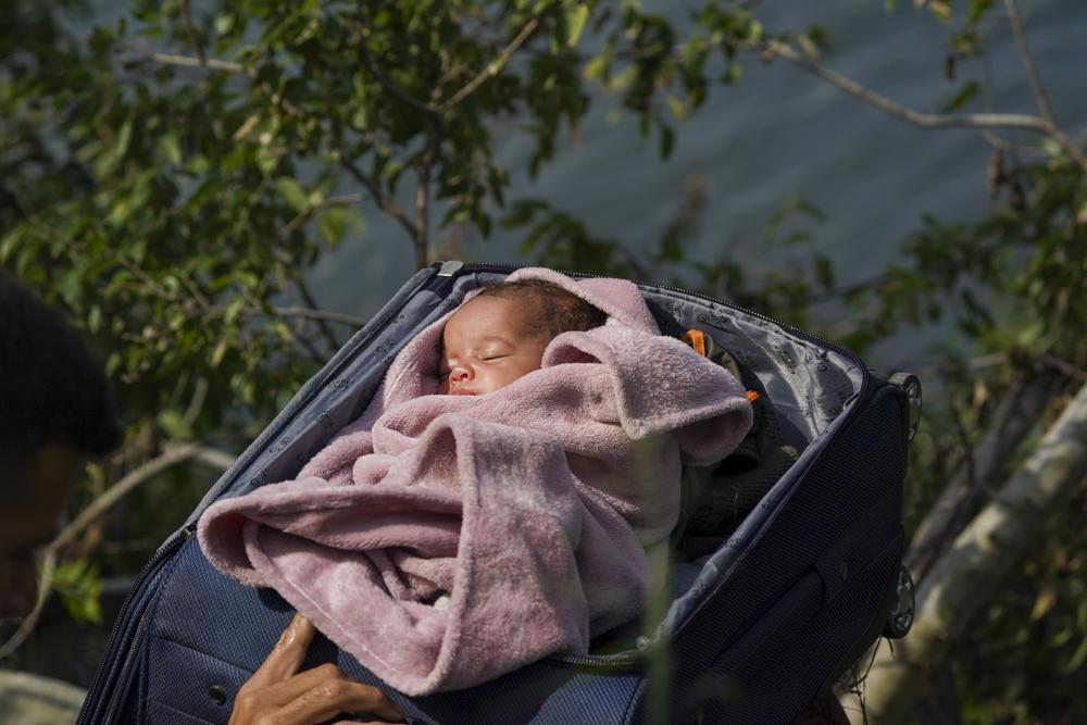 Người di cư vượt sông Rio Grande vào Mỹ với một em bé trong vali, nhìn từ Matamoros, Mexico, hôm 5/10. (Ảnh: AP)