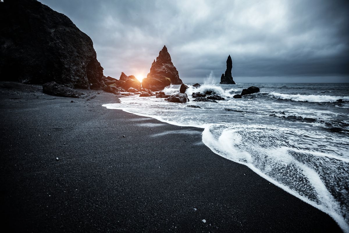 Những bãi biển cát đen ở Iceland giống như một khung cảnh siêu thực trong một bộ phim giả tưởng hoành tráng. Có một cái gì đó ảm đạm nhưng đầy mê hoặc về những con sóng xanh thẳm vỗ vào bãi cát đen như than. Các bãi biển đặc biệt có màu sẫm do nguồn gốc núi lửa của chúng. Dung nham bắt nguồn từ một ngọn núi lửa không hoạt động, chảy vào bãi biển và nguội đi nhanh chóng khi tiếp xúc với nước biển lạnh. Do quá trình nguội đi nhanh chóng này, dung nham đông đặc lại thành đá bazan, sau đó bị xói mòn, dần dần vỡ ra thành các mảnh nhỏ hơn, cuối cùng tạo thành cát đen.