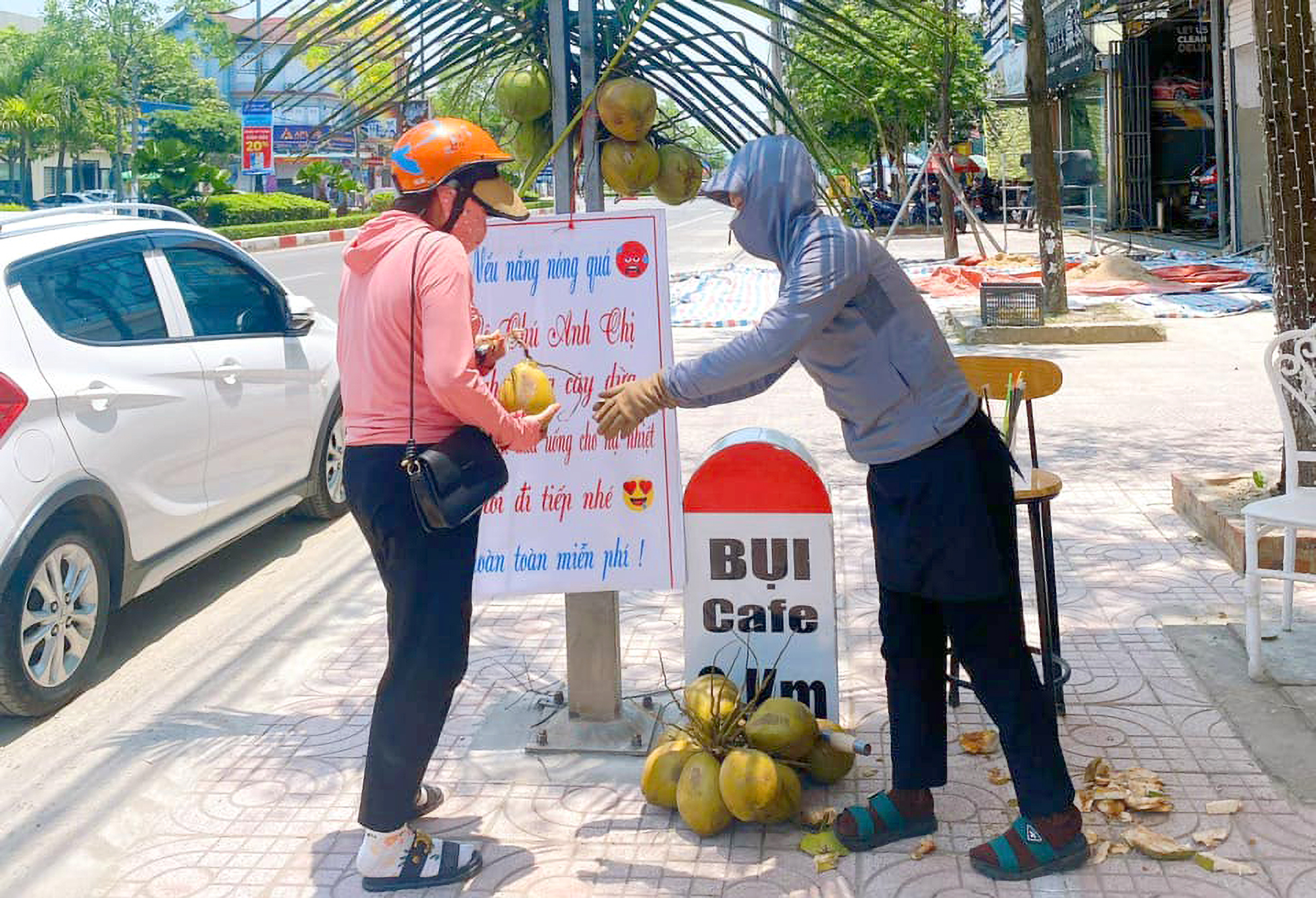 Nhân viên thay nhau túc trực để chặt dừa, cắm ống hút rồi trao tận tay cho người dân - Ảnh: Khánh Trung