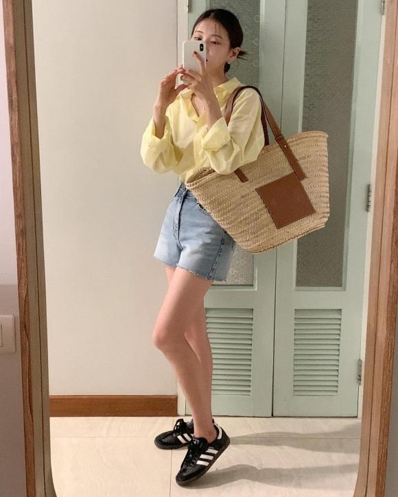 Áo sơ mi phom rộng màu vàng pastel kết hợp với quần short, túi cói giúp chị em có được set đồ du lịch mùa hè sành điệu, hợp mốt.