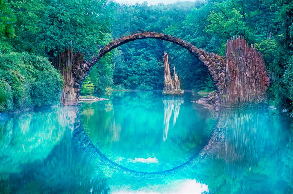 Cầu Quỷ, Đức Rakotzbrücke đẹp đến mức có lẽ nên gọi là cây cầu trong truyện cổ tích thì đúng hơn. Nhưng tên của nó, có nghĩa là Cầu Quỷ, xuất phát từ các liên tưởng siêu nhiên của nó. Cấu trúc vòng lặp, ở thị trấn Kromlau của Đức, tạo thành một vòng tròn hoàn hảo với hình ảnh phản chiếu dưới nước – một thủ thuật kỹ thuật thông minh mà một số người coi là ở thế giới khác.
