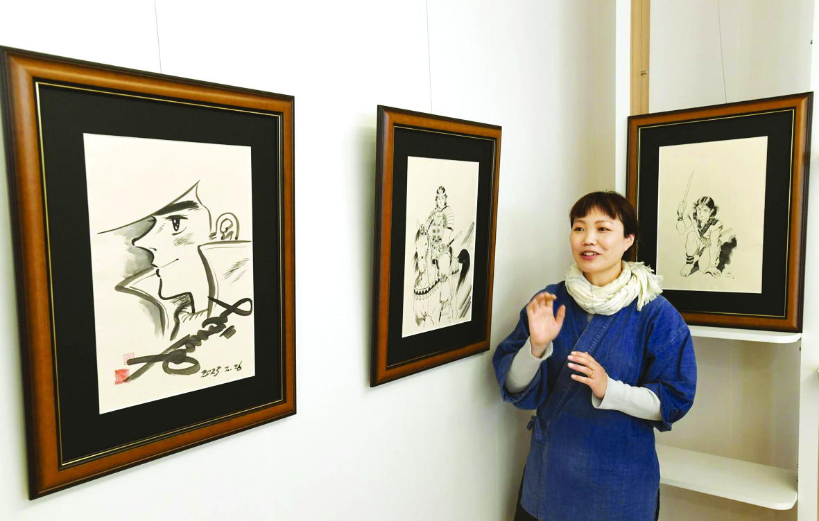Nghệ nhân Naho Murata đứng cạnh những bức vẽ trên giấy washi tại Bảo tàng Giấy và Văn hóa ở Echizen, tỉnh Fukui - ẢNH: KYODO