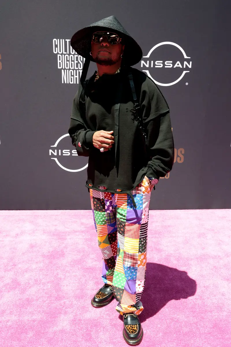 Rapper K.O trang bị cho mình một chiếc áo khoác chùm đầu đen đơn giản. Bù lại phần chân nổi bật với chiếc quần dài được may từ nhiều chất liệu sáng màu. Chiếc mũ kasa đen bóng và đôi giày lười da báo cũng nâng tầm phong cách cho anh chàng rapper này.