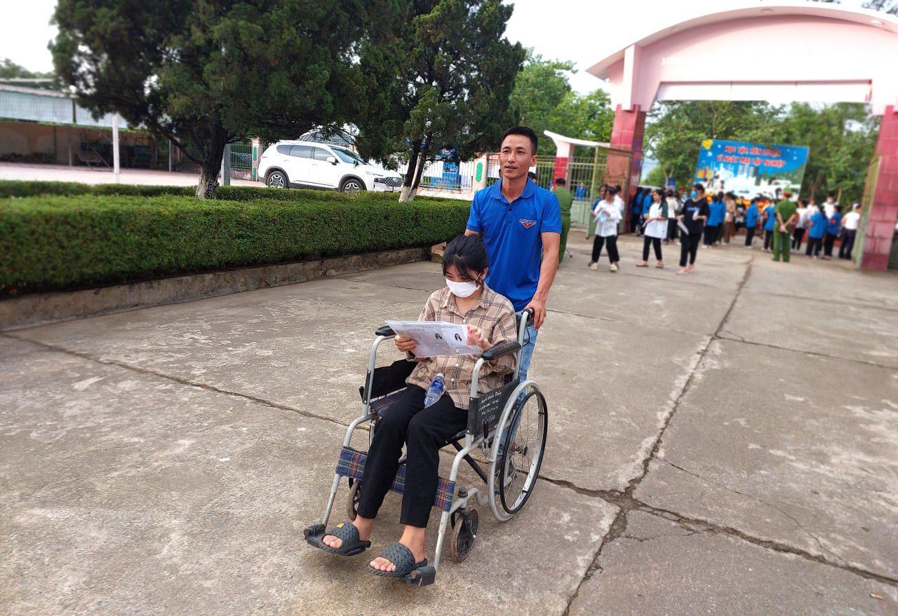 Quyên được thanh niên tình nguyện đưa vào phòng thi bằng xe lăn - Ảnh: Khánh Trung