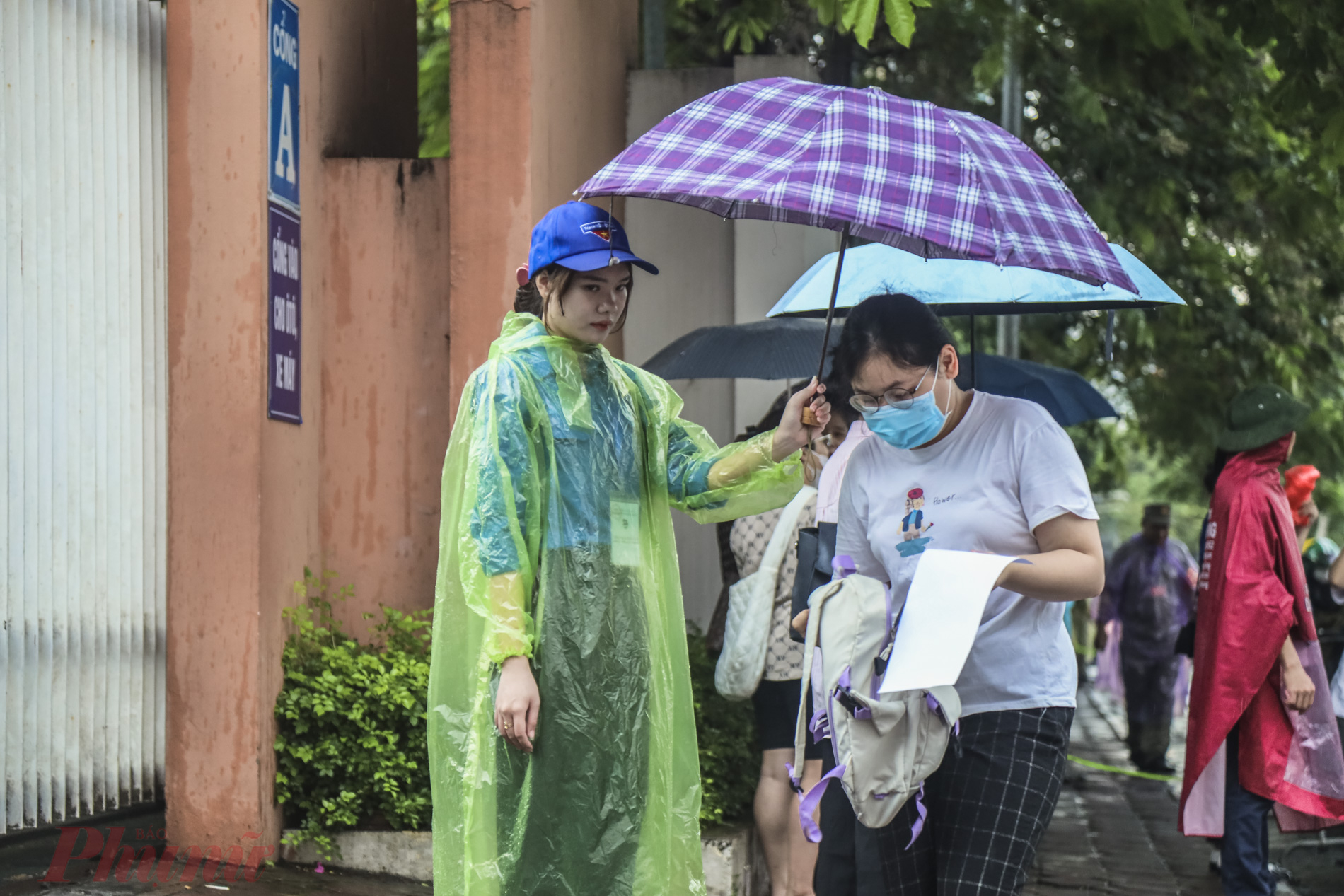 Thanh niên tình nguyện che ô hỗ trợ các thí sinh vào phòng thi.