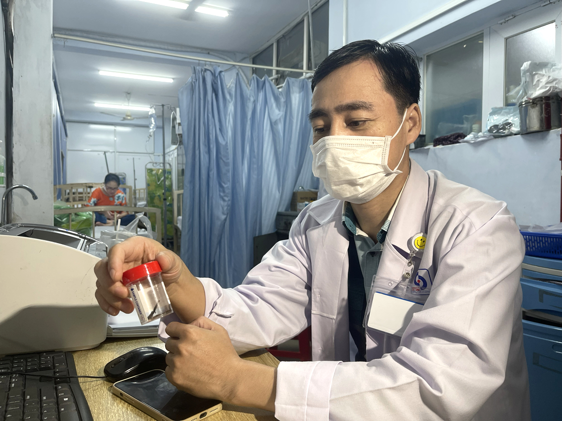 Bác sĩ chuyên khoa 2 Ngô Quang Duy - Khoa Ngoại tiêu hóa Bệnh viện Nhân dân Gia Định - và mảnh vỏ sò lấy từ ruột non của cụ bà 86 tuổi