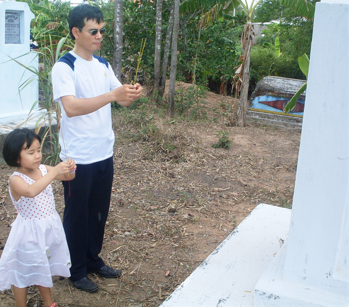 Em trai và con gái của tác giả thắp hương trước mộ bà trong một lần về thăm quê