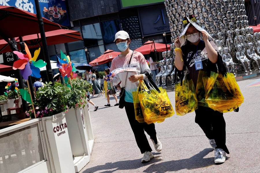 Người dân che nắng khi đi bộ giữa đợt nắng nóng ở Bắc Kinh, vào ngày 23/6. (Ảnh: REUTERS)
