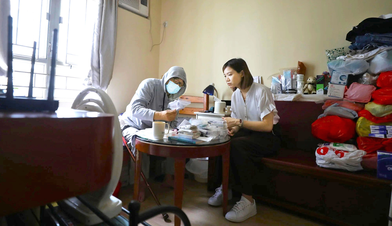 Cô Yuen trò chuyện và hướng dẫn sử dụng đơn thuốc cho ông Ah Wah (62 tuổi), sống một mình trong căn hộ chung cư ở khu Sham Shui Po, Hồng Kông (Trung Quốc) - ẢNH: XIAOMEI CHEN/SCMP