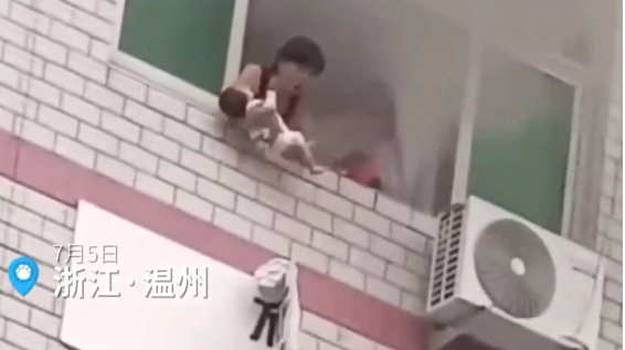 Người mẹ tuyệt vọng bế đứa con 40 ngày tuổi của mình bên ngoài cửa sổ của căn hộ ở tầng ba đang bốc cháy chỉ vài giây trước khi để đứa trẻ sơ sinh ra đi. Ảnh: Weibo