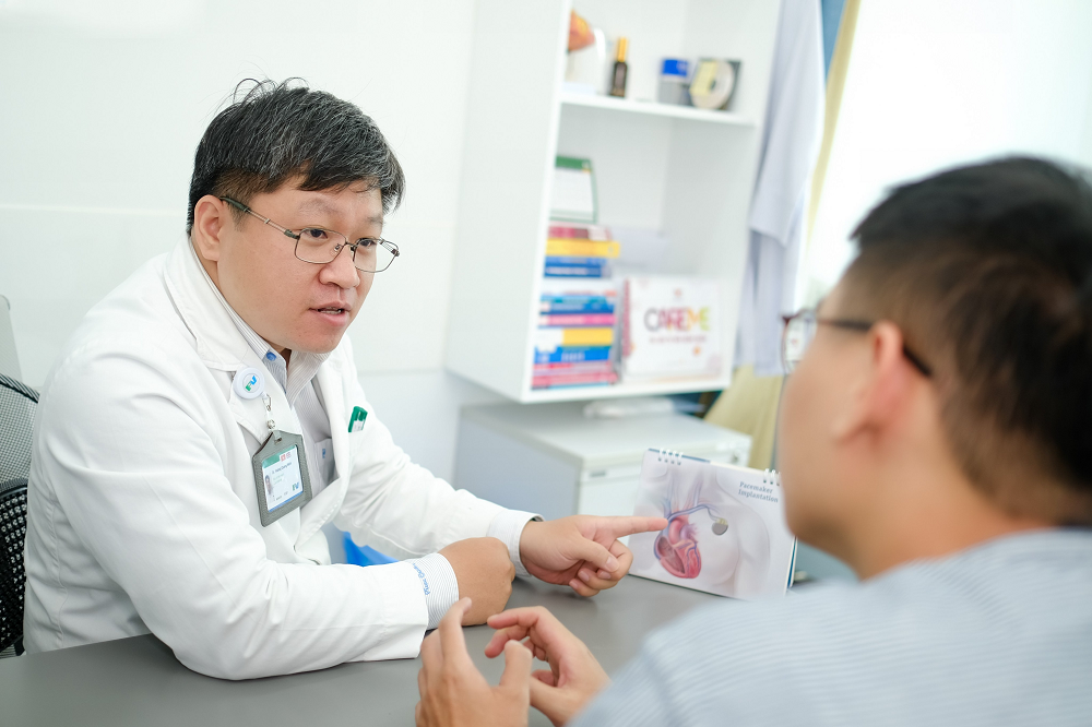 Bác sĩ Hoàng Quang Minh tư vấn cho bệnh nhân về điều trị rung nhĩ - Ảnh: FV