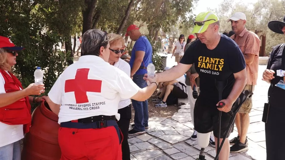 Tình nguyện viên từ Hội Chữ thập đỏ Hy Lạp, Hy Lạp phát nước cho du khách