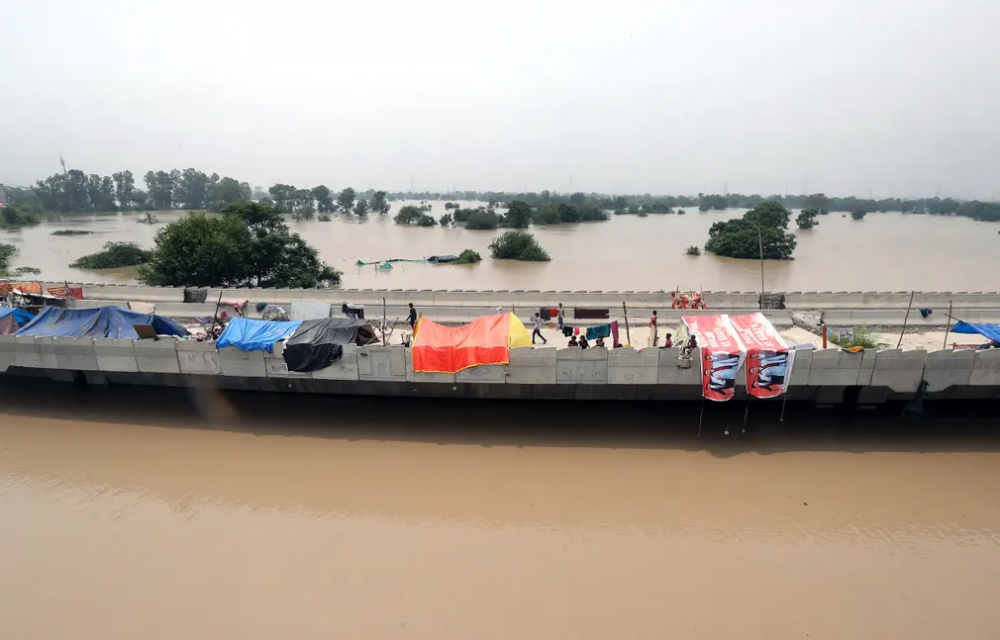 Người dân trú ẩn trên một cây cầu gần sông Yamuna ở New Delhi, Ấn Độ vào ngày 13/7, giữa cảnh lũ lụt.(Ảnh: Harish Tyagi/EPA)