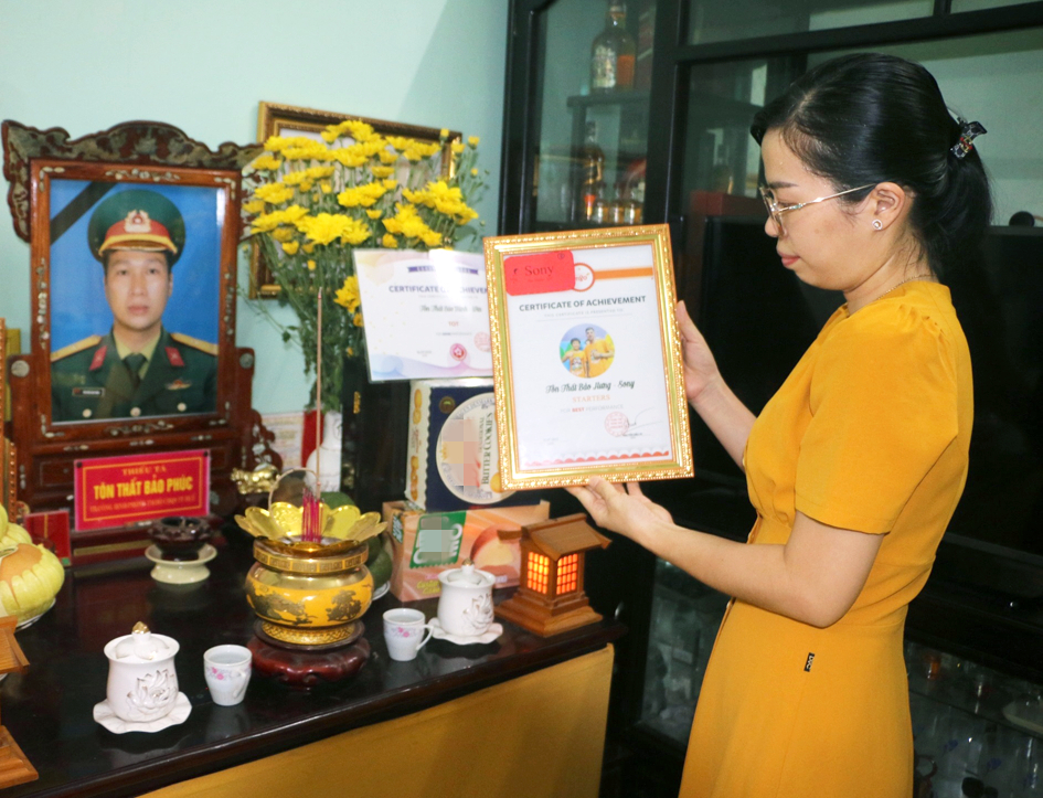 Thượng úy Phùng Hữu Hoàng Trang bên di ảnh chồng là thiếu tá, liệt sĩ Tôn Thất Bảo Phúc 